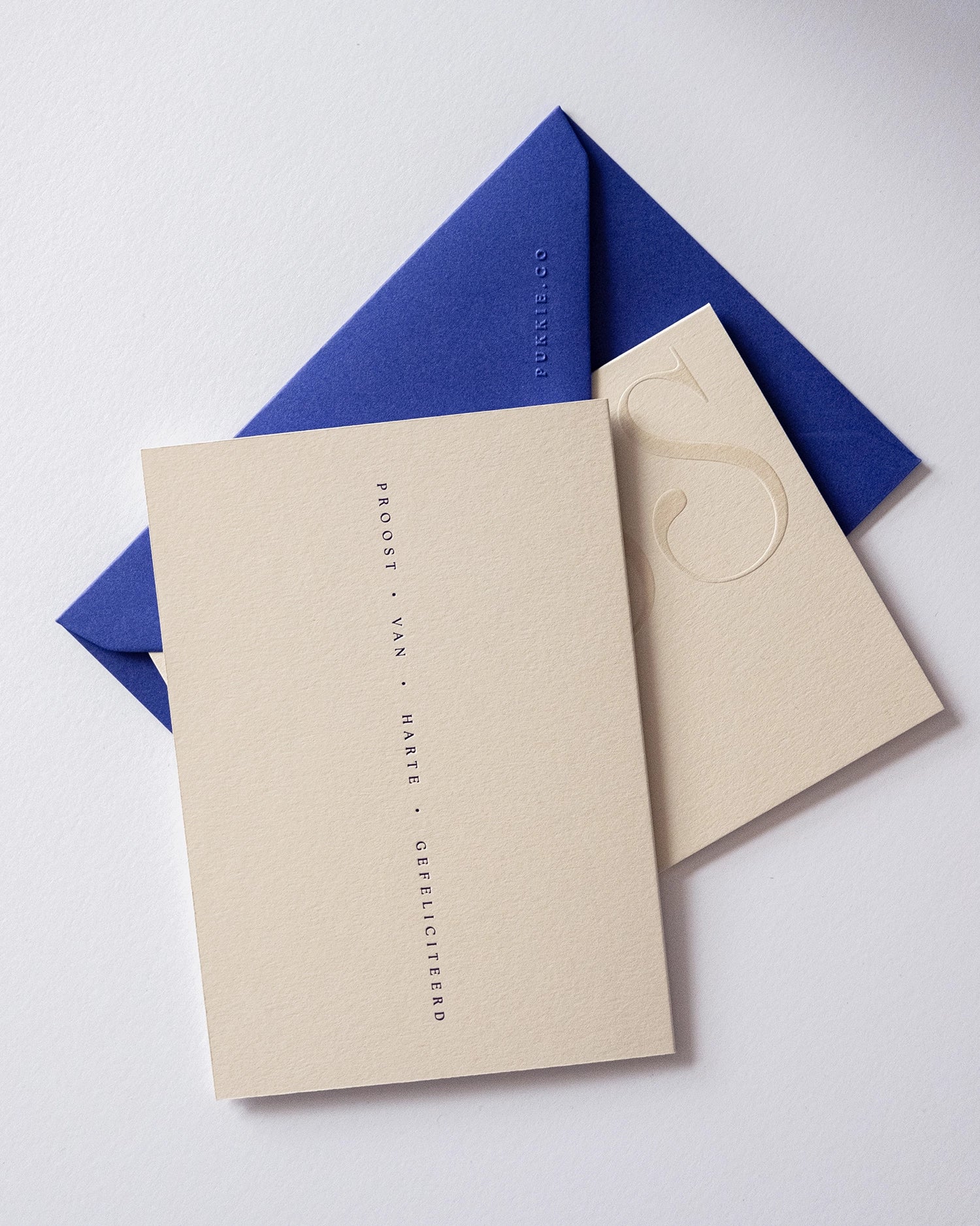 Flat lay of minimal luxury embossed greeting cards from the minimal collection with royal blue envelop