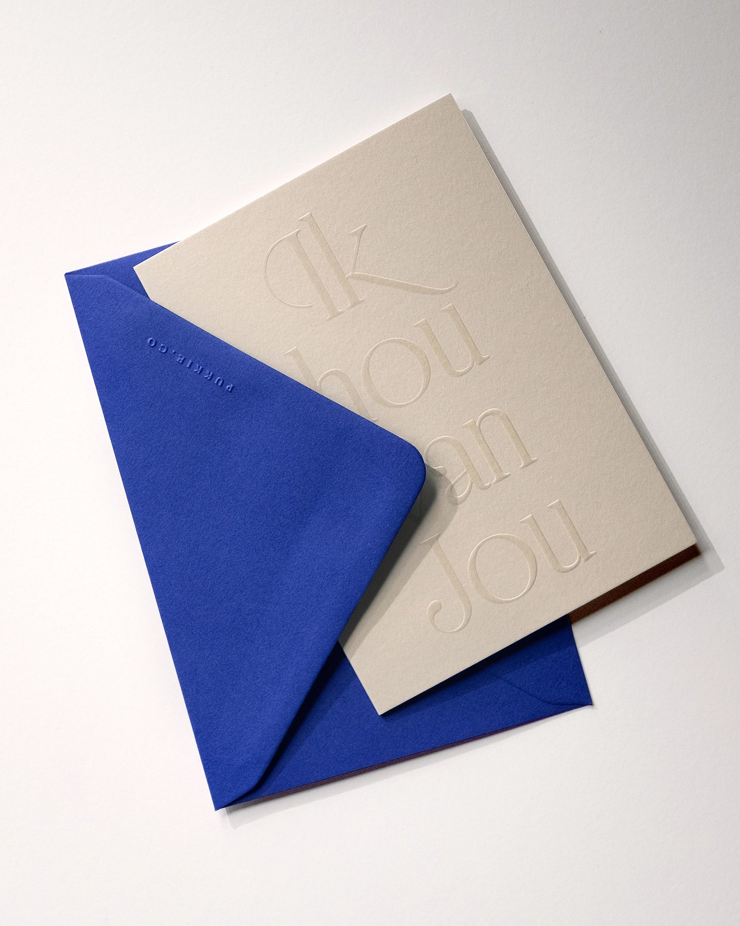 Flat lay of minimal luxury embossed greeting card “ik hou van jou” with envelope folded over card on Colorplan Mist paper