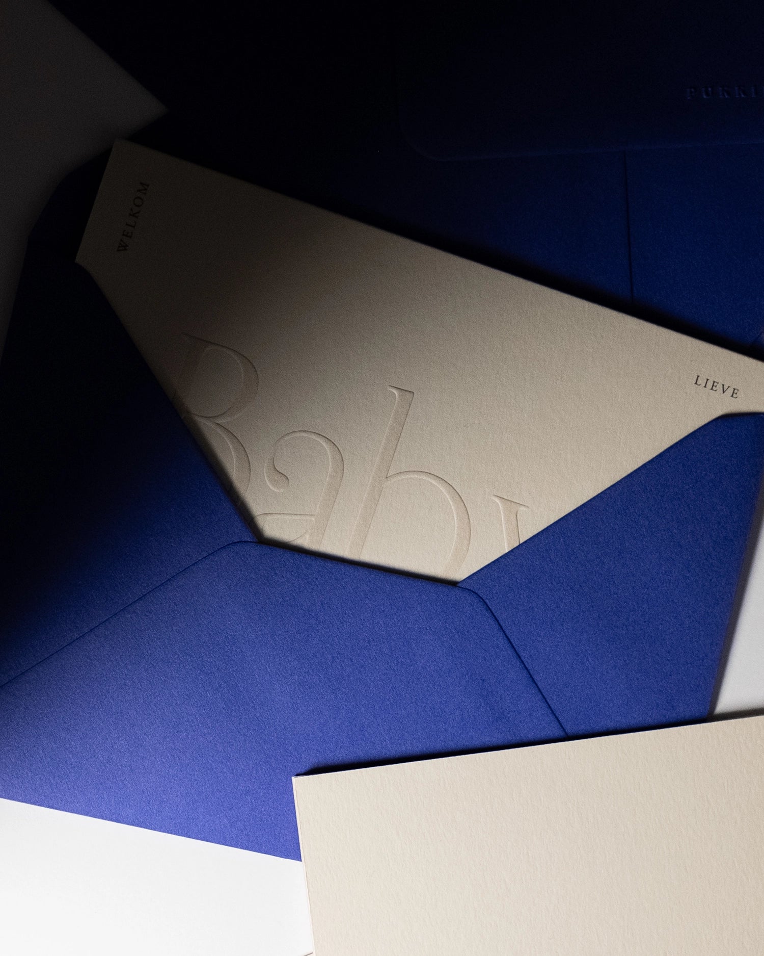 minimal luxury greeting card “Welkom lieve kleine baby” inside royal blue envelopwith shadows on Colorplan Mist paper