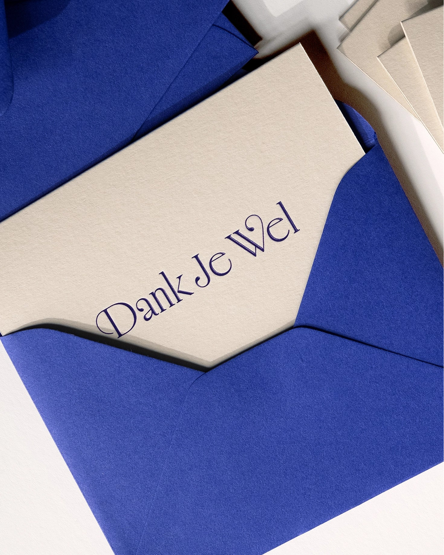 Close-up of minimal luxury letterpress thank you card “dank je wel” with royal blue envelope on Colorplan Mist paper