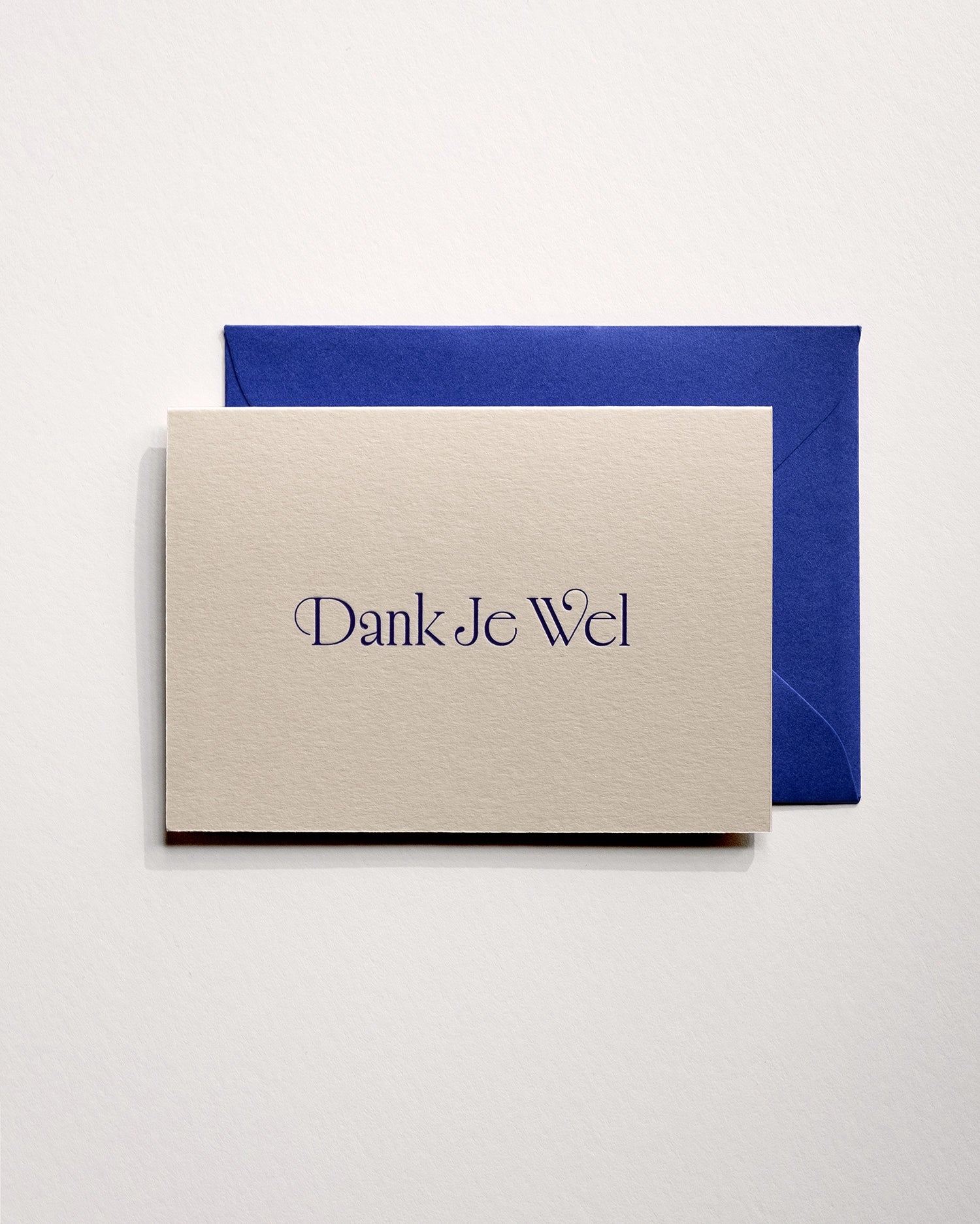 Top view of minimal luxury letterpress thank you card “dank je wel” on Colorplan Mist paper with royal blue envelope