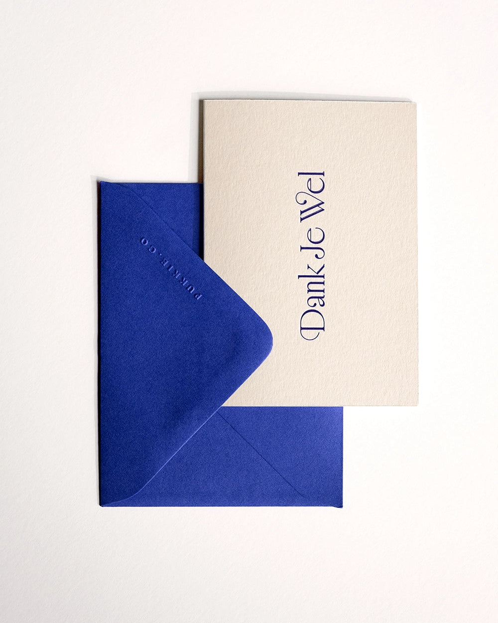 Flat lay of minimal luxury letterpress thank you card “dank je wel” with envelope folded over card on Colorplan Mist paper