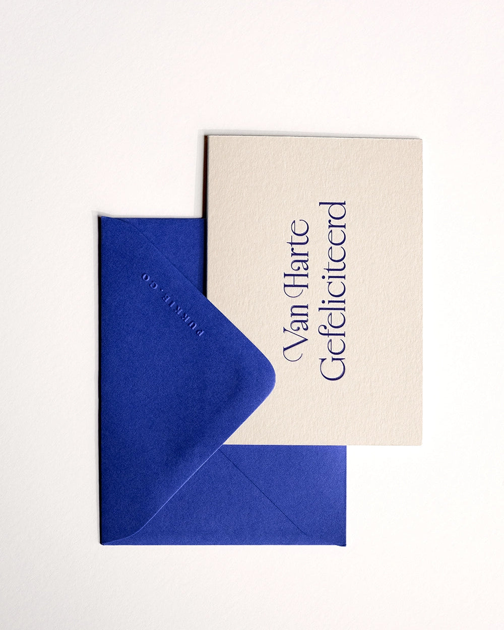 Flat lay of minimal luxury letterpress brithday card “van harte gefeliciteerd” with envelope folded over card on Colorplan Mist paper